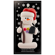 Snowman in red hat holding walking stick and binoculars, on display backing card.