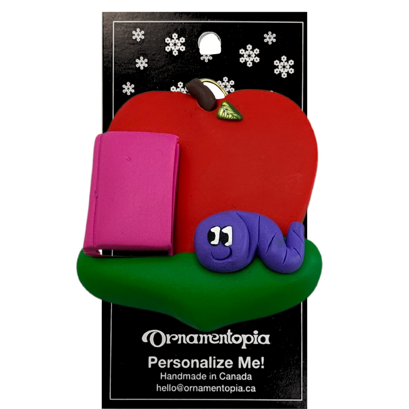 Red apple with pink book and purple worm teacher appreciation ornament, on display backing card.