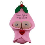 Ornament with twin infant heads poking out of a pink baby blanket, personalized with names.