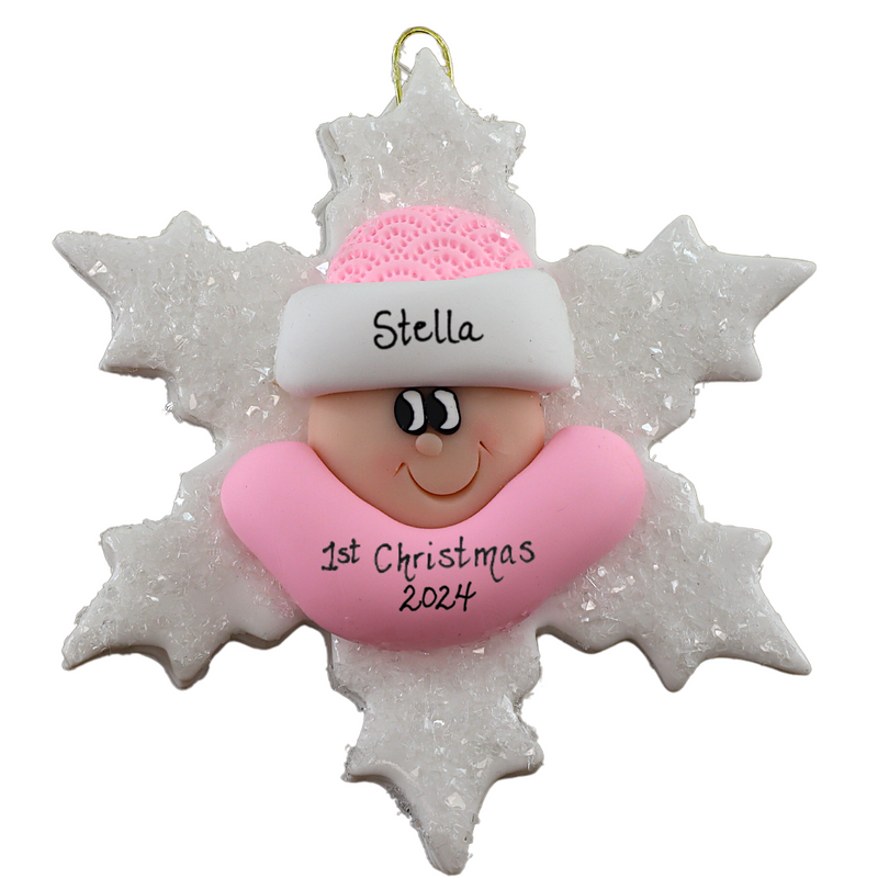 Baby ornament with infant face and pink hat on glittery white snowflake base, personalized with name.