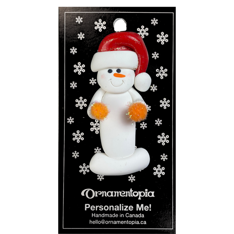 Ornament of white snowman in red hat holding orange cheerleader pom-poms, on display backing card.