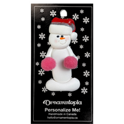 Ornament of white snowman in red hat holding pink cheerleader pom-poms, on display backing card.