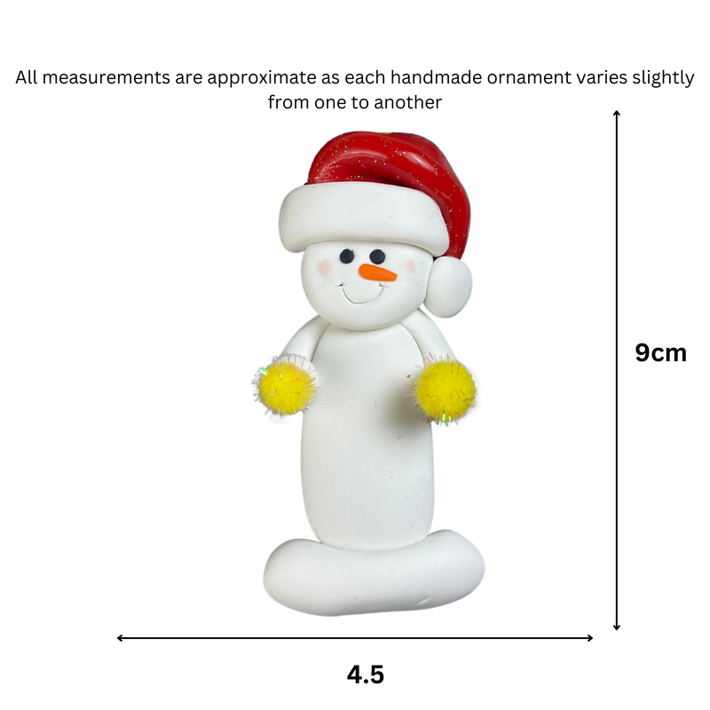 Ornament of white snowman in red hat holding yellow cheerleader pom-poms, graphed to show size (4.5x9cm).