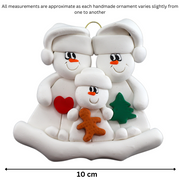 Family ornament with 2 large and 1 small snowmen in hats, holding holiday objects, graphed to show size (10cm).