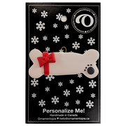Ornament of dog bone with ribbon and paw print, on display backing card.