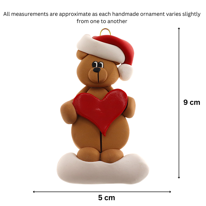 Tan bear in red festive hat holding red heart ornament, graphed to show size (5x9cm).