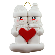 A couple’s ornament of two white snowmen holding a red heart together.