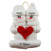 A couple’s ornament of two white snowmen holding a red heart together, personalized with names.