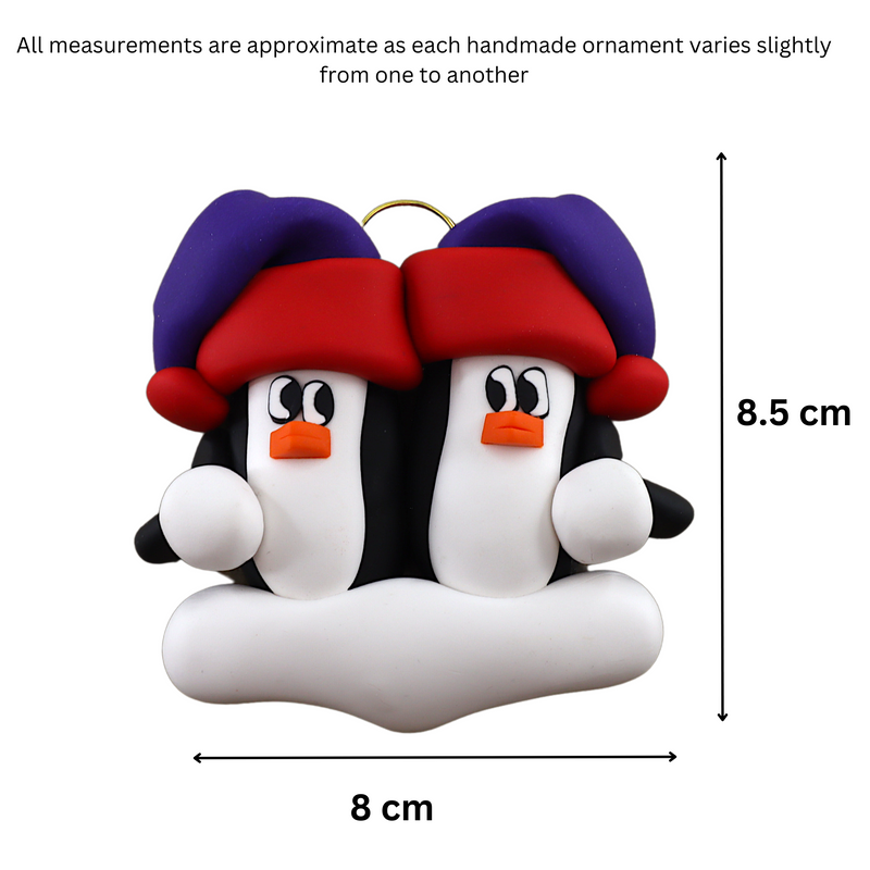 A couple’s ornament of two penguins in colourful hats, graphed to show size (8x8.5cm).