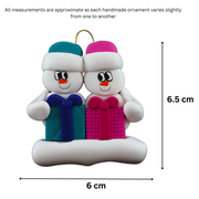 Family ornament with 2 white snowmen in colourful hats holding matching presents, graphed to show size (6x6.5cm).