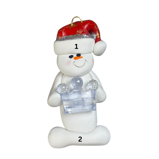 Ornament of white snowman in red hat holding clear plastic crown, numbered 1-2 for personalization.