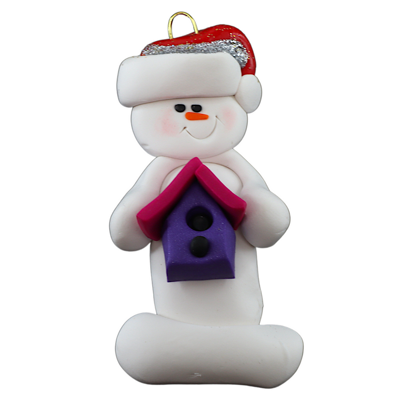 Ornament of white snowman in red hat holding a pink and purple birdhouse.