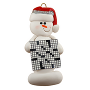 Ornament of white snowman in red hat holding large crossword puzzle.