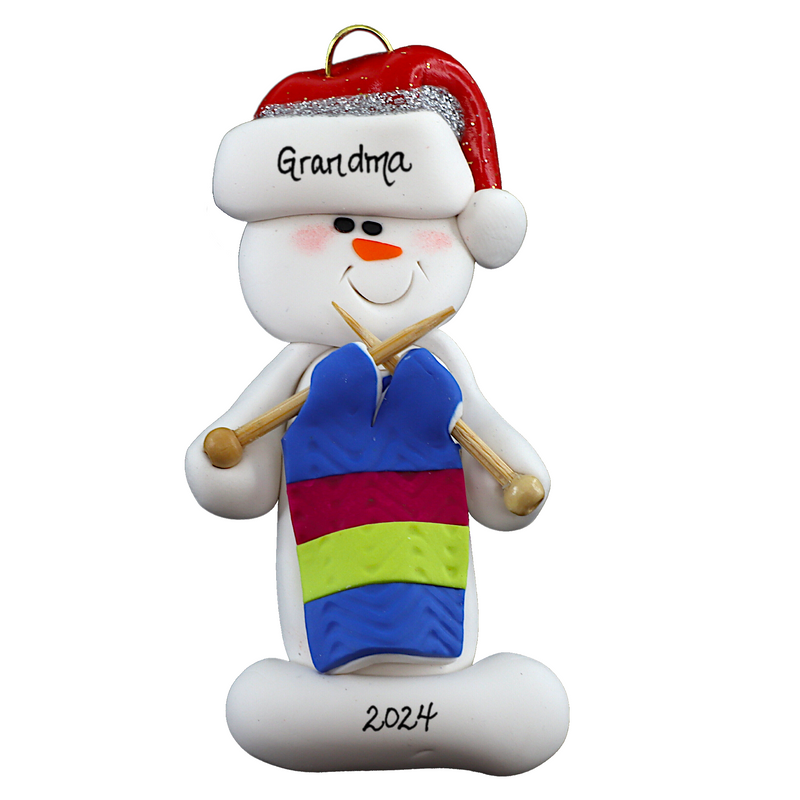Ornament of white snowman in red hat holding an in-progress knitting project on knitting needles, numbered 1-2 for personalization.