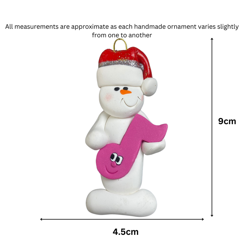 Ornament of white snowman in red hat holding a pink music note, graphed to show size (4.5x9cm).