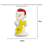 Ornament of white snowman in red hat holding a yellow music note, graphed to show size (4.5x9cm).