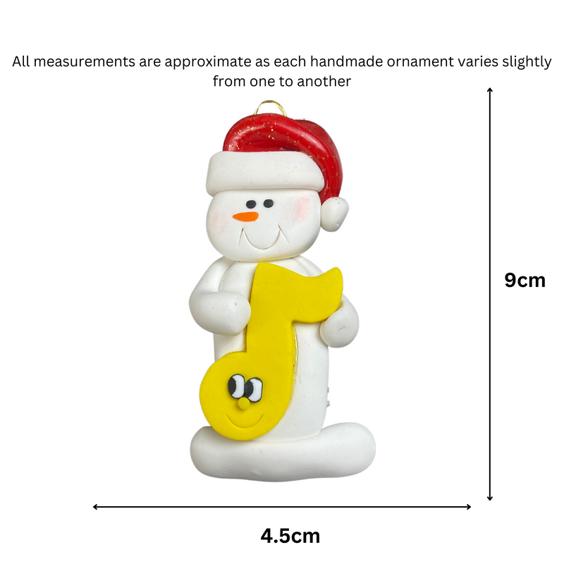 Ornament of white snowman in red hat holding a yellow music note, graphed to show size (4.5x9cm).