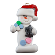 Ornament of white snowman in red hat holding various pills and a mortar and pestle, shown on backing card and Christmas tree.