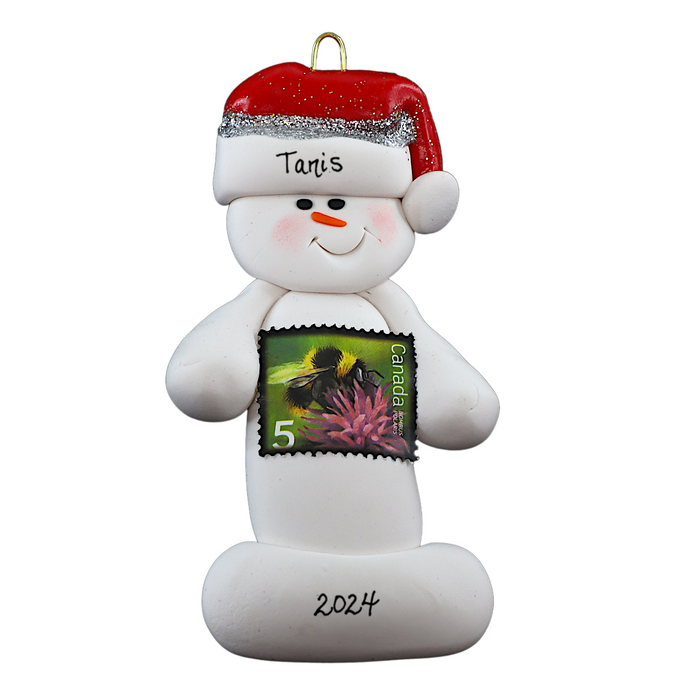 Ornament of white snowman in red hat holding a postal stamp, personalized with name.
