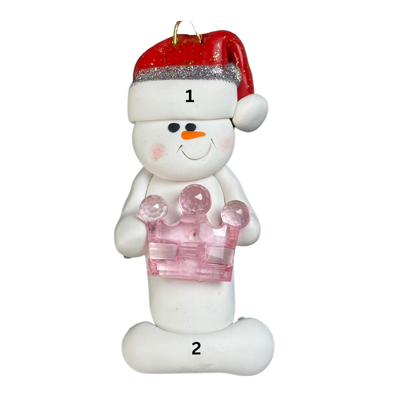 Ornament of white snowman in red hat holding a pink plastic crown, numbered 1-2 for personalization.