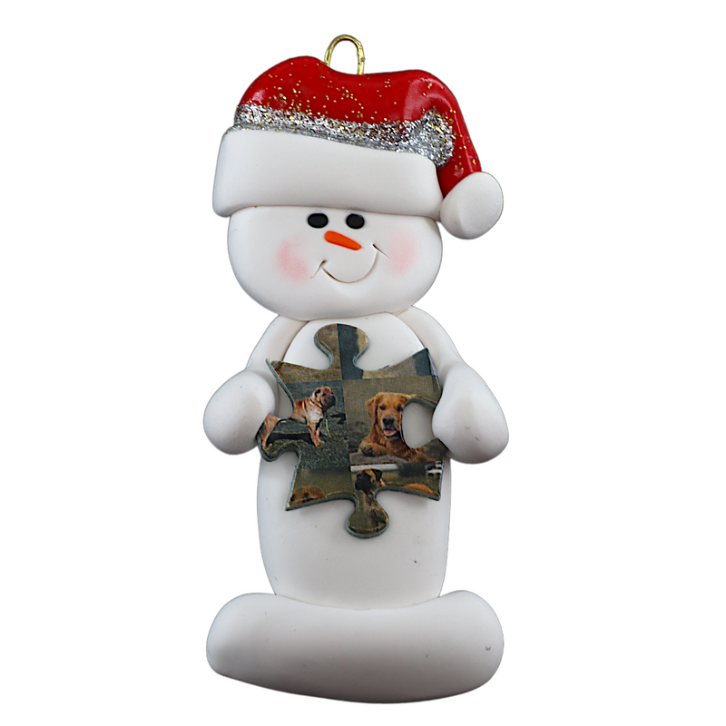 Ornament of white snowman in red hat holding a puzzle piece.