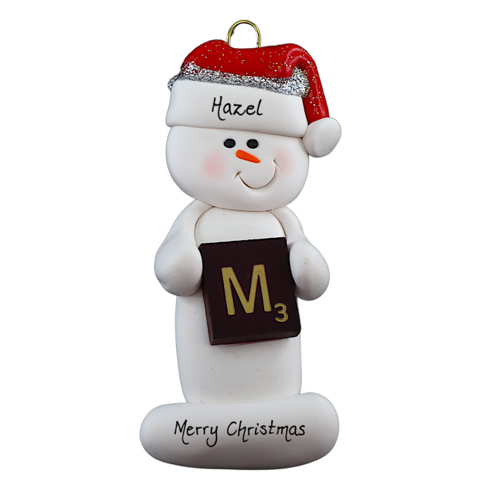 Ornament of white snowman in red hat holding a scrabble tile, personalized with name.
