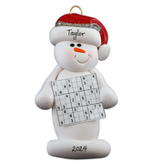 Ornament of white snowman in red hat holding a sudoku page, personalized with name.
