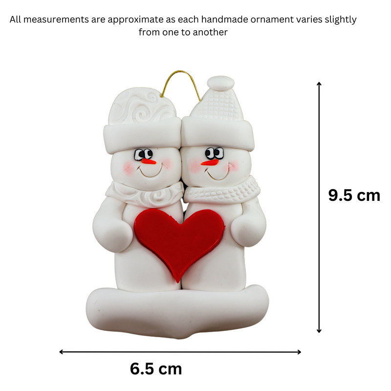 A couple’s ornament of two white snowmen holding a red heart together, graphed to show size (6.5x9.5cm).