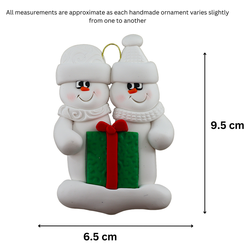 A couple’s ornament of two white snowmen holding a vibrant present, graphed to show size (6.5x9.5cm).