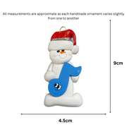 Ornament of white snowman in red hat holding a blue music note, graphed to show size (4.5x9cm).