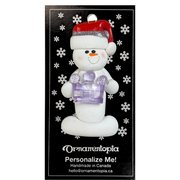 Ornament of white snowman in red hat holding purple plastic crown, on display backing card.