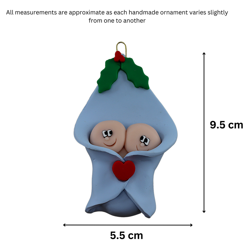 Ornament with twin infant heads poking out of a blue baby blanket, graphed to show size (5.5x9.5cm).