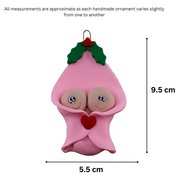 Ornament with twin infant heads poking out of a pink baby blanket, graphed to show size (5.5x9.5cm).
