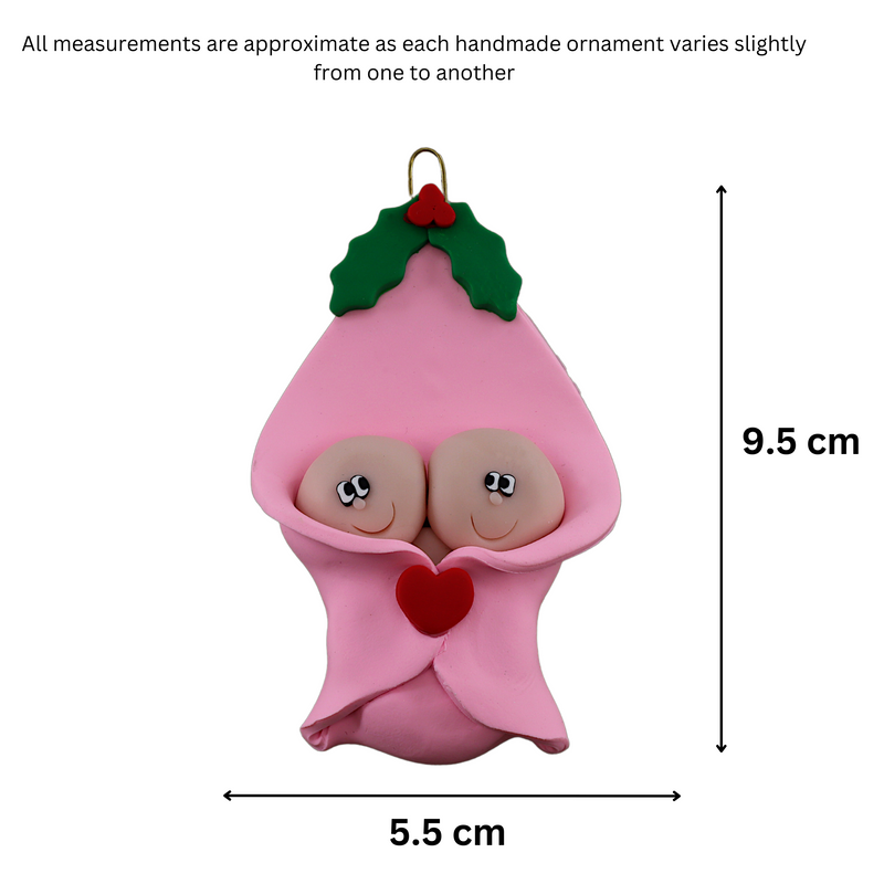 Ornament with twin infant heads poking out of a pink baby blanket, graphed to show size (5.5x9.5cm).