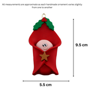 Ornament with an infant head poking out of a red baby blanket, graphed to show size (5.5x9.5cm).