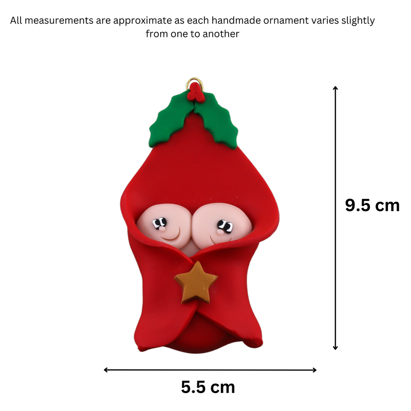 Ornament with twin infant heads poking out of a red baby blanket, graphed to show size (5.5x9.5cm).
