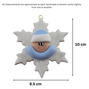 Baby ornament with infant face and blue hat on glittery white snowflake base, graphed to show size (8.5x10cm).