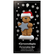 Tan bear in red festive hat holding silver star ornament, on display backing card.