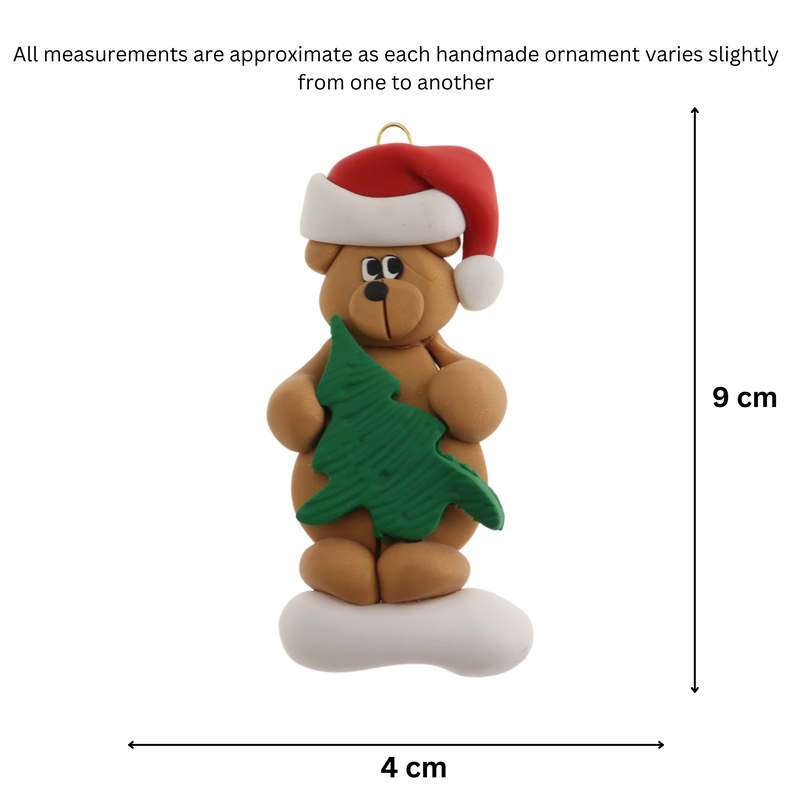 Tan bear in red festive hat holding green tree ornament, graphed to show size (4x9cm).