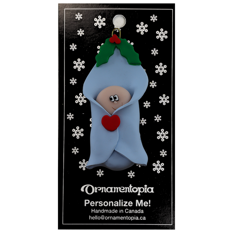 Ornament with infant head poking out of a blue baby blanket, on display backing card.