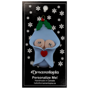 Ornament with twin infant heads poking out of a blue baby blanket, on display backing card.