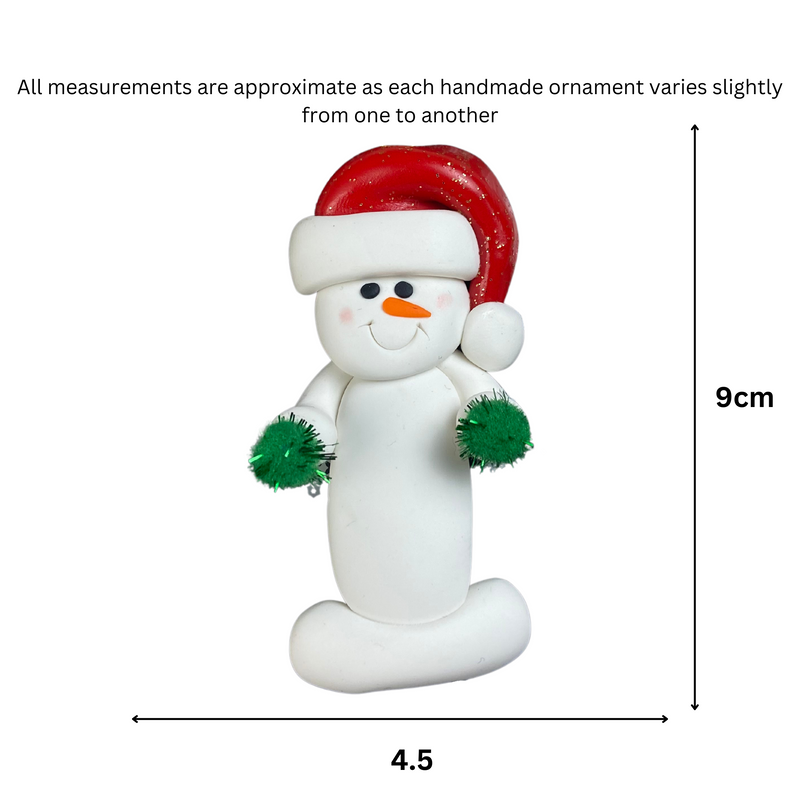 Ornament of white snowman in red hat holding green cheerleader pom-poms, graphed to show size (4.5x9cm).