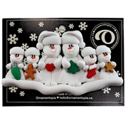 Family ornament with 2 large and 4 small white snowmen in hats, holding holiday objects, on display backing card.