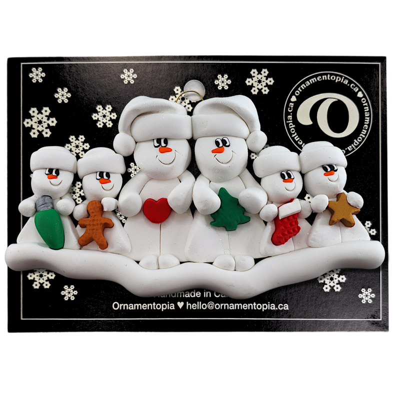 Family ornament with 2 large and 4 small white snowmen in hats, holding holiday objects, on display backing card.