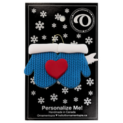 A couple’s ornament of two mittens cradling a heart, on display backing card.