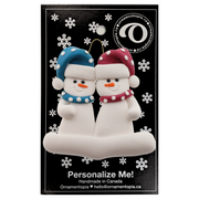 A couple’s ornament of two white snowmen in polka dot scarves and hats, on display backing card.