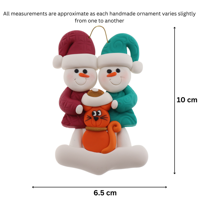 Ornament of snowman couple in red and green shirts and hats with a orange cat in Christmas hat, graphed to show size (6.5x10cm).