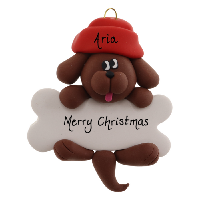Ornament of brown dog in red hat hanging on a white bone, personalized with names.