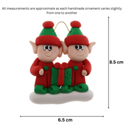 A couple’s ornament with two small red and green elves with a matching present, graphed to show size (6.5x8.5cm).