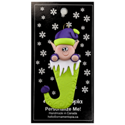 Elf poking out of green stocking ornament, on display backing card.